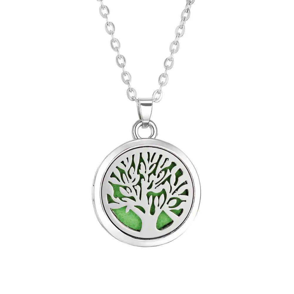 Collar difusor de aromaterapia en acero inoxidable con diseño de árbol y fondo verde, ideal para aceites esenciales.