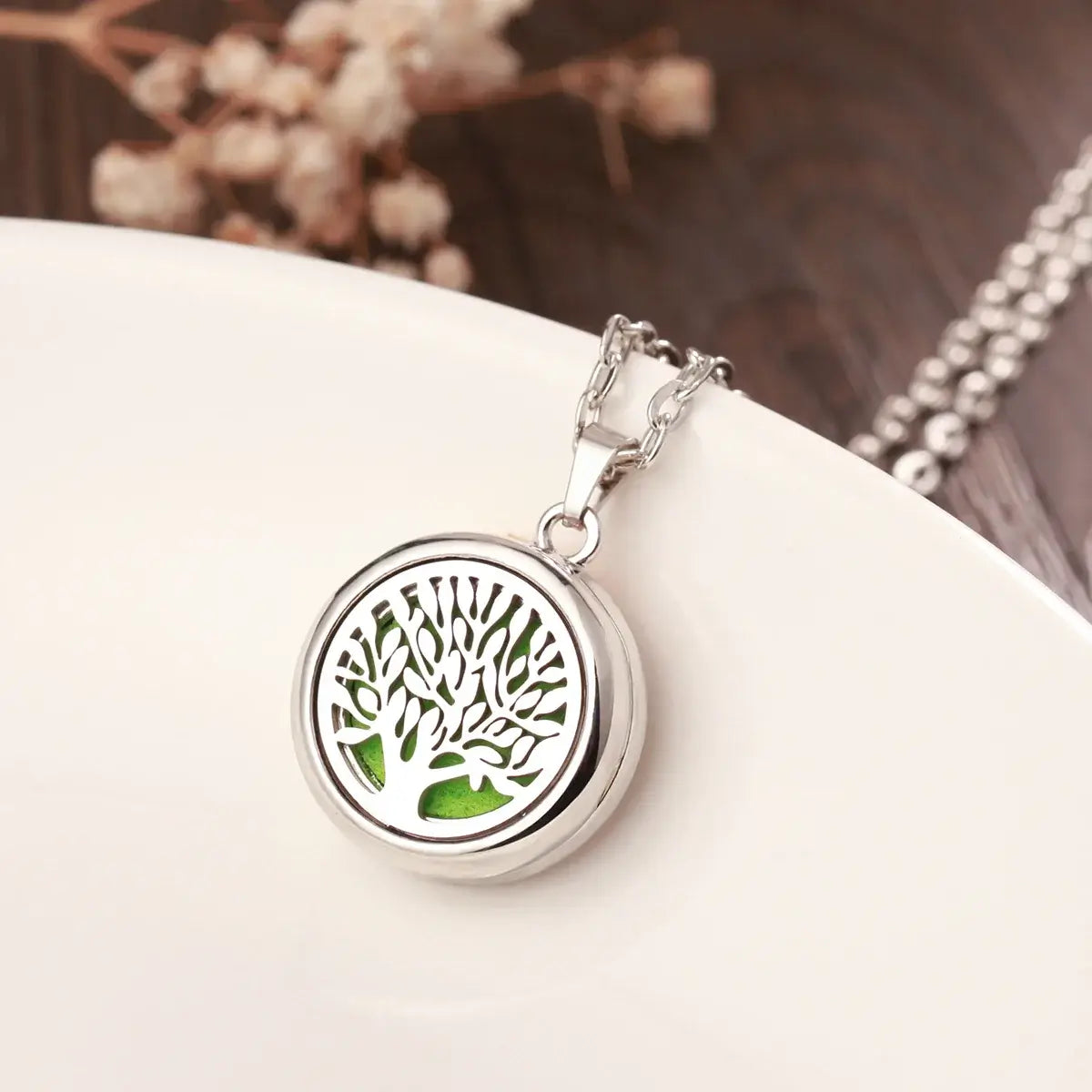 Elegante collar difusor de aromaterapia en acero inoxidable con diseño de árbol y espacio para aceites esenciales.
